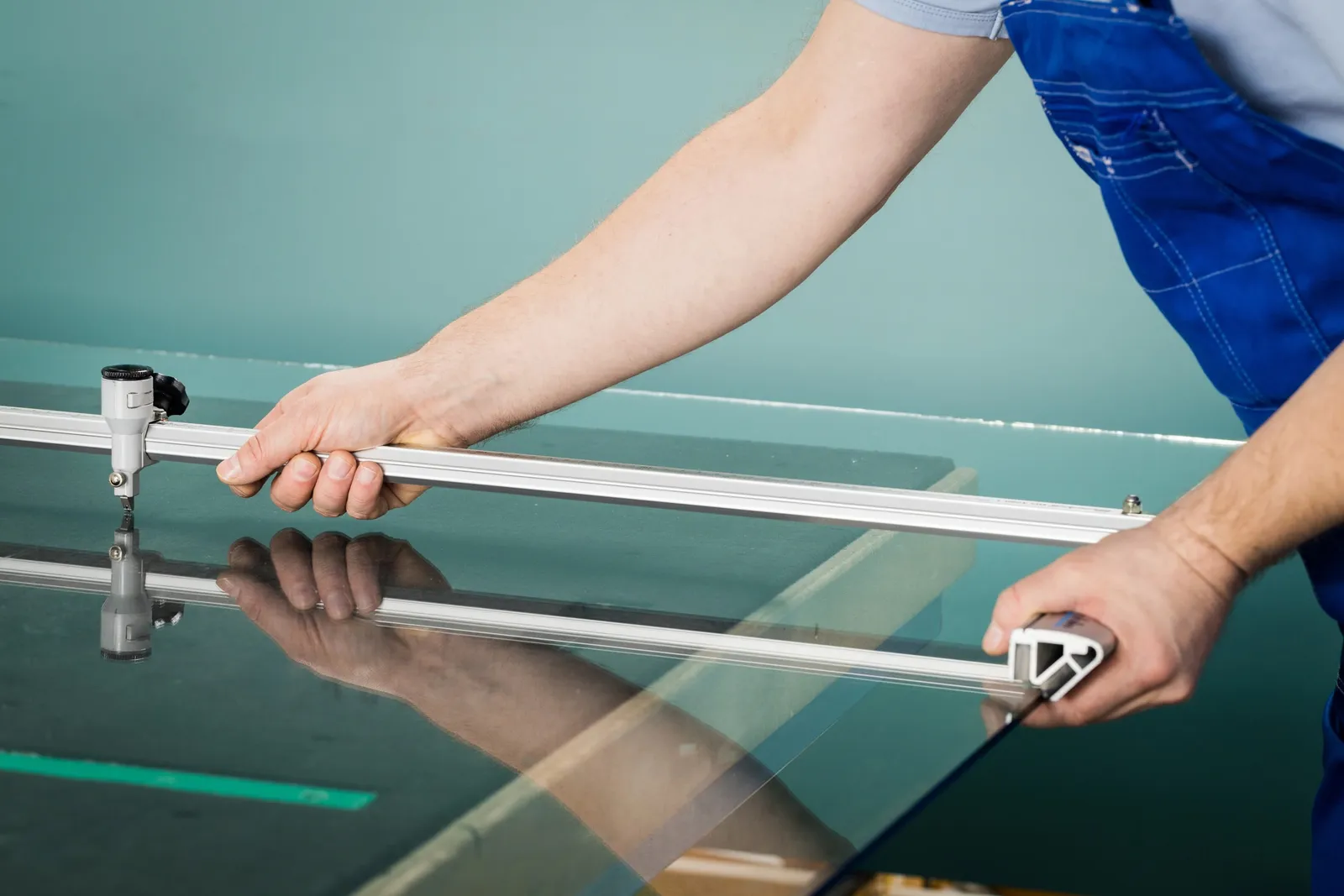 Découpe d'un panneau de verre au coupe-verre sur table d'atelier